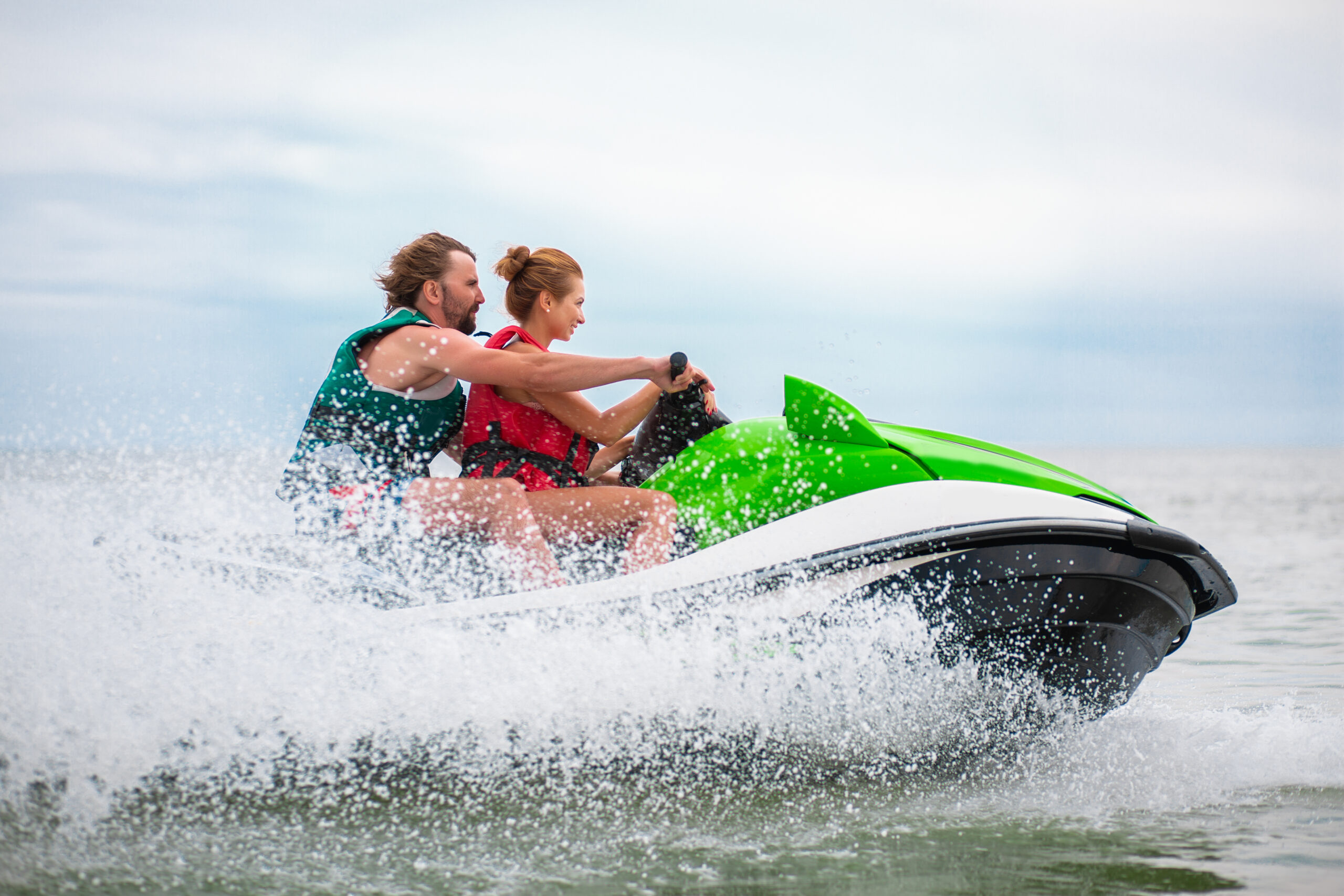 young people having fun driving on high speed on water scooter, man and woman on summer vacation, friends doing active sport